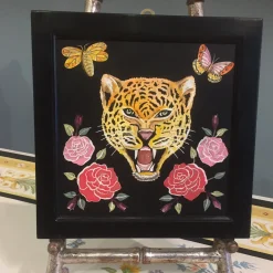 Scagliola dipinge un felino con fiori e insetti